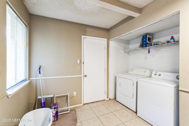 laundry room featuring washing machine and clothes dryer, baseboards, laundry area, light tile patterned flooring, and a textured ceiling