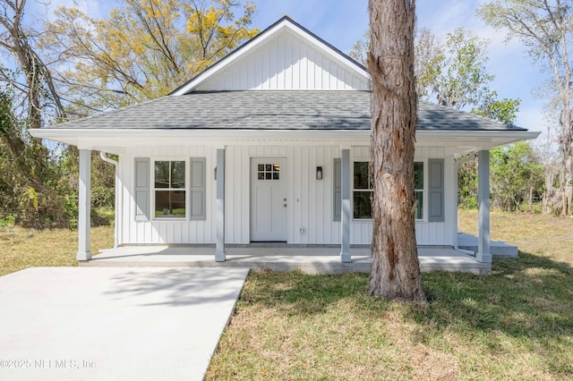 view of front of house featuring a porch, board and batten siding, a shingled roof, and a front yard