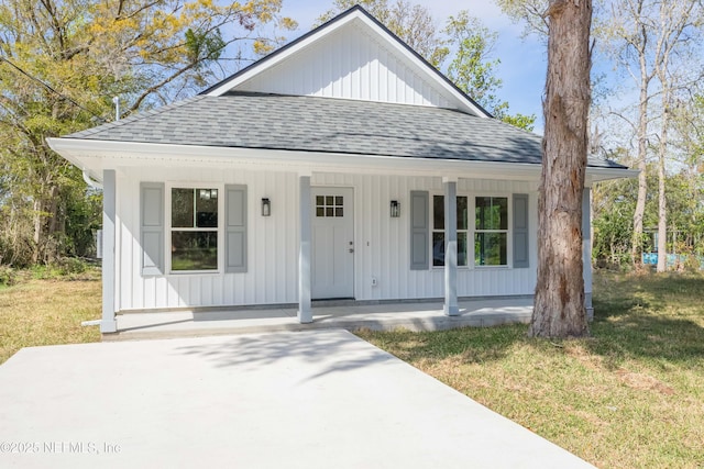 view of front facade featuring a porch, a front yard, and roof with shingles