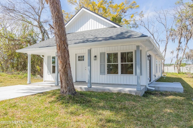 bungalow-style home with a front yard, a porch, board and batten siding, and a shingled roof