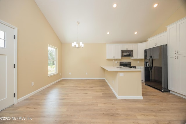 kitchen with a peninsula, black appliances, light countertops, white cabinetry, and light wood-type flooring