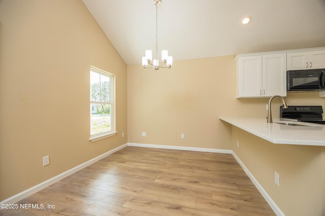 kitchen featuring white cabinetry, black microwave, light wood finished floors, light countertops, and vaulted ceiling