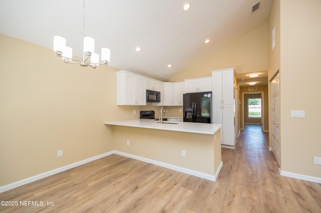 kitchen with visible vents, a peninsula, black appliances, light countertops, and white cabinetry