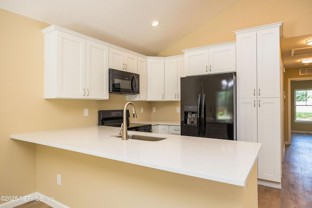 kitchen featuring a peninsula, a sink, black appliances, vaulted ceiling, and light countertops