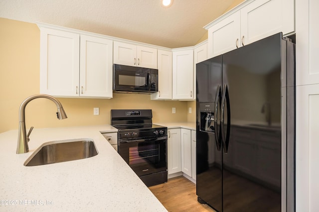 kitchen with black appliances, white cabinets, light wood-type flooring, and a sink