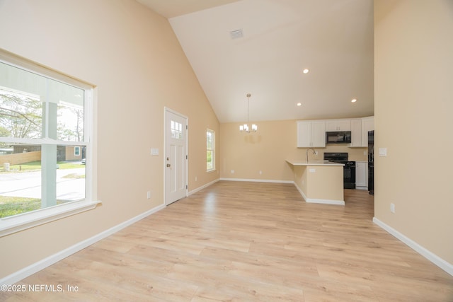 kitchen with visible vents, high vaulted ceiling, black appliances, an inviting chandelier, and white cabinets