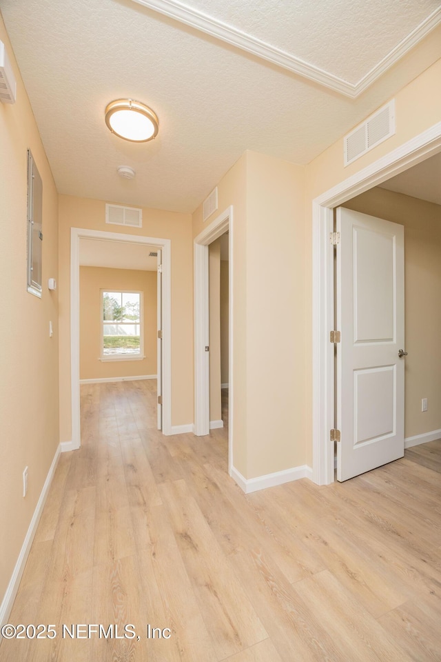 hallway with visible vents, baseboards, and light wood-style floors