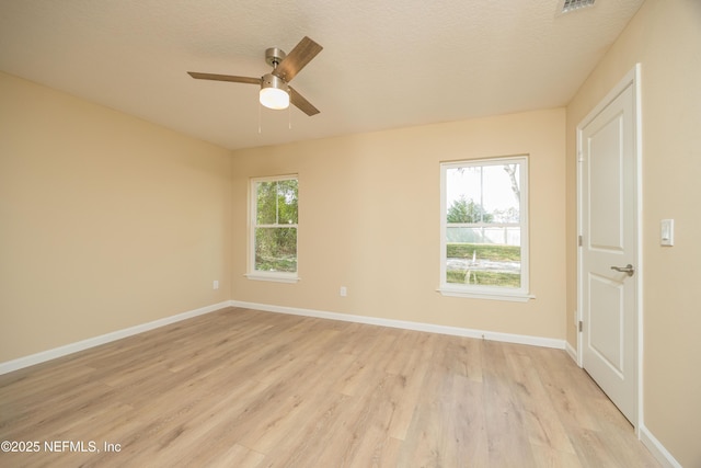 spare room featuring light wood finished floors, ceiling fan, a textured ceiling, and baseboards