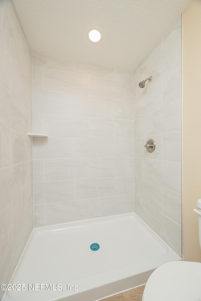 bathroom with toilet and a tile shower