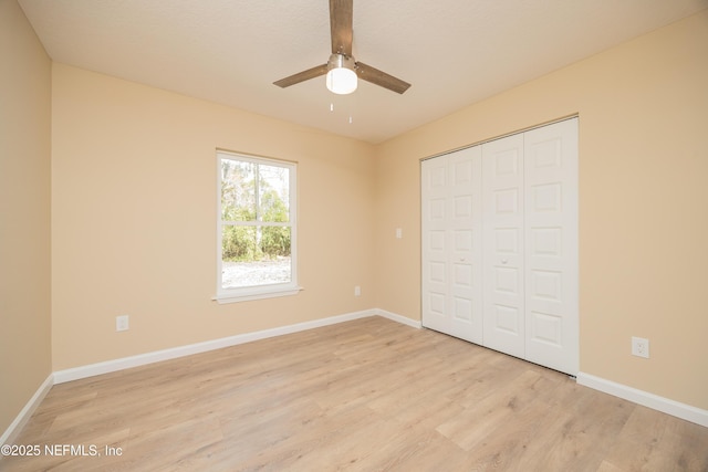 unfurnished bedroom featuring a closet, baseboards, light wood-style floors, and a ceiling fan