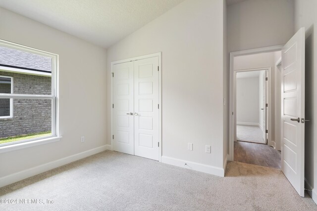 unfurnished bedroom with vaulted ceiling, multiple windows, and carpet