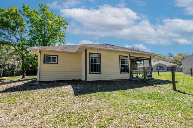 back of property featuring a carport, a lawn, and fence