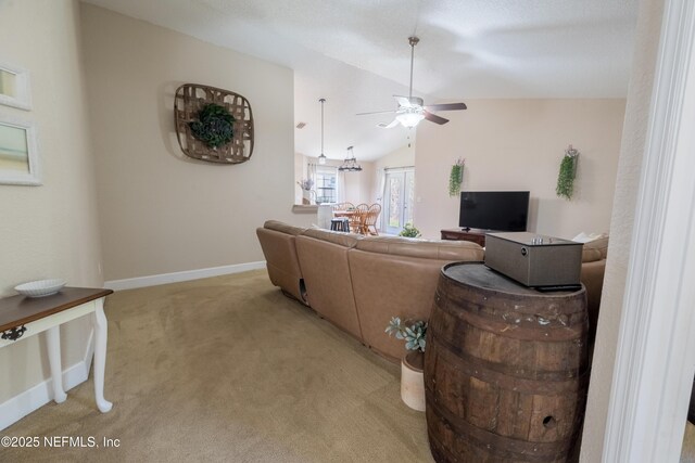 living room featuring light colored carpet, a ceiling fan, baseboards, and vaulted ceiling