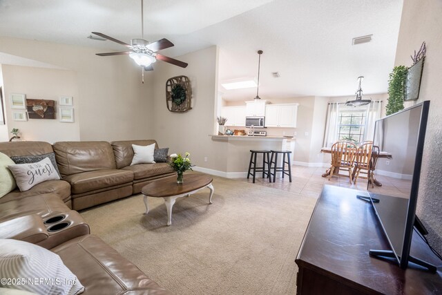 living room with visible vents, baseboards, lofted ceiling, light carpet, and light tile patterned floors