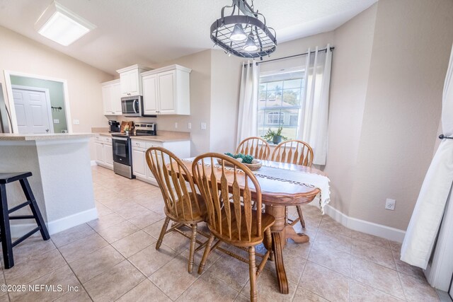 dining room featuring light tile patterned flooring, baseboards, and vaulted ceiling