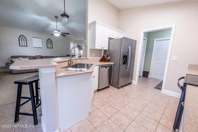 kitchen with a peninsula, a sink, light countertops, appliances with stainless steel finishes, and white cabinetry