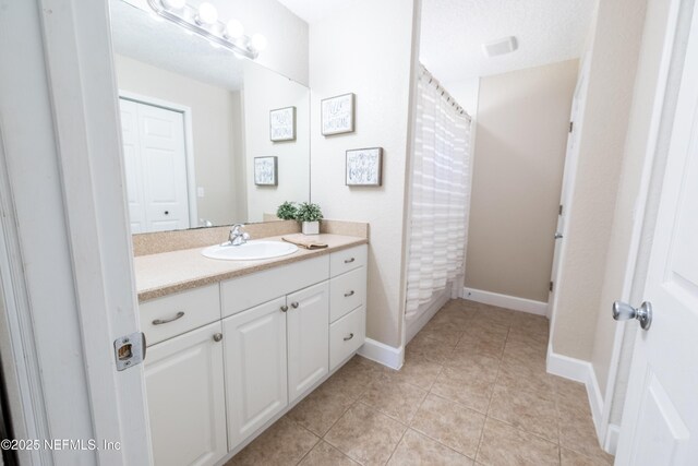 full bath featuring tile patterned floors, curtained shower, baseboards, and vanity