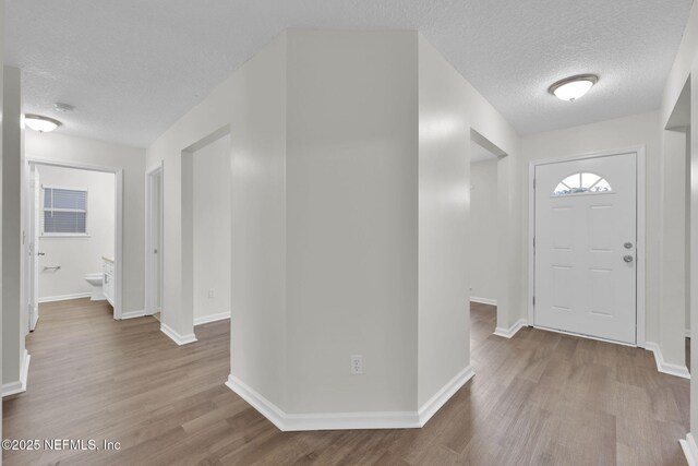 entryway with wood finished floors, baseboards, and a textured ceiling