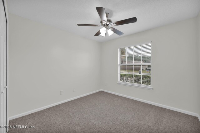 carpeted spare room with baseboards and ceiling fan