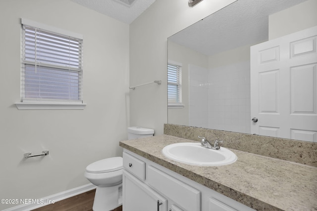 full bathroom with toilet, a textured ceiling, wood finished floors, baseboards, and vanity