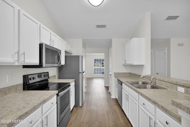 kitchen with visible vents, white cabinets, appliances with stainless steel finishes, and a sink