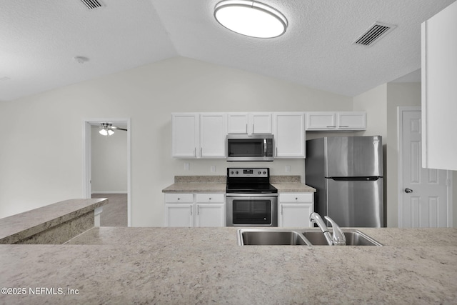 kitchen with visible vents, a sink, stainless steel appliances, white cabinets, and vaulted ceiling