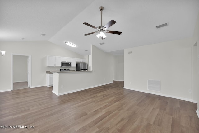 unfurnished living room featuring visible vents, light wood finished floors, lofted ceiling, and ceiling fan with notable chandelier