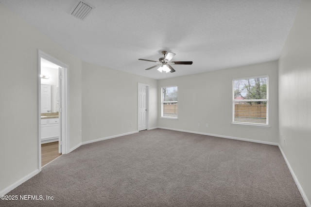 unfurnished room featuring visible vents, baseboards, carpet floors, a textured ceiling, and a ceiling fan