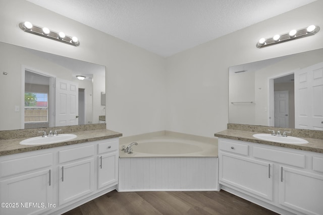 bathroom featuring a textured ceiling, two vanities, and a sink