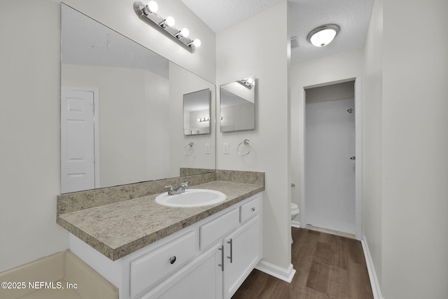 bathroom featuring vanity, wood finished floors, a shower, a textured ceiling, and toilet