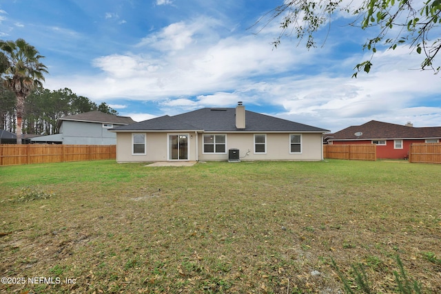 rear view of house with stucco siding, central air condition unit, a lawn, and a fenced backyard