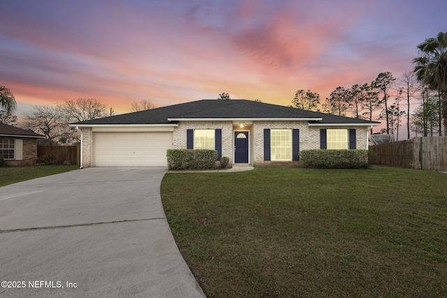 ranch-style house featuring driveway, fence, a yard, a garage, and brick siding