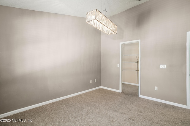 empty room featuring baseboards, carpet floors, and a chandelier