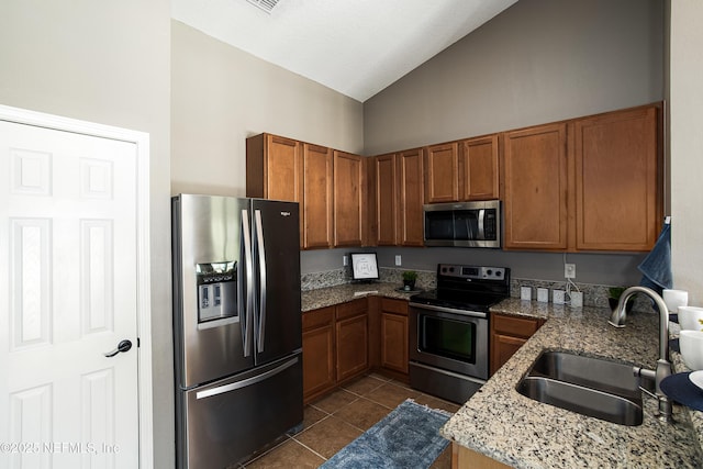 kitchen featuring a sink, brown cabinets, dark tile patterned flooring, and appliances with stainless steel finishes