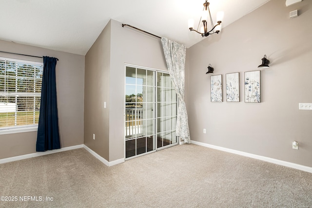 carpeted empty room featuring a chandelier, baseboards, and vaulted ceiling