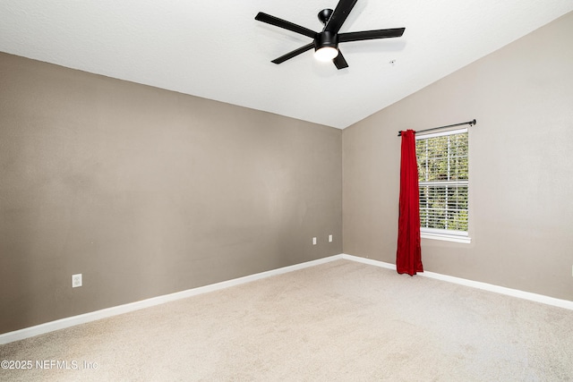 empty room with a ceiling fan, vaulted ceiling, carpet, and baseboards