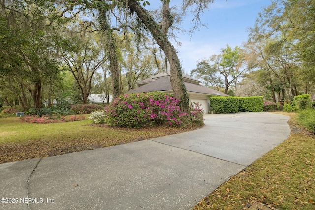 view of side of property with an attached garage, a lawn, and driveway