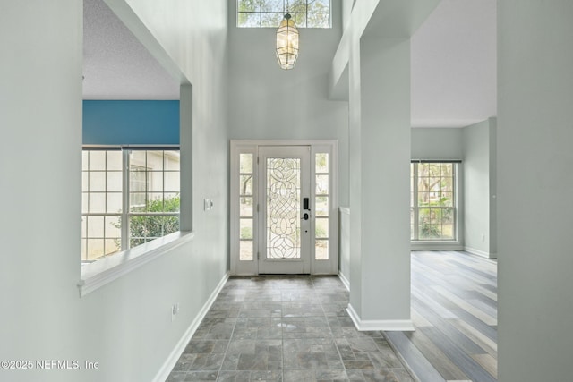 entryway with baseboards and a towering ceiling