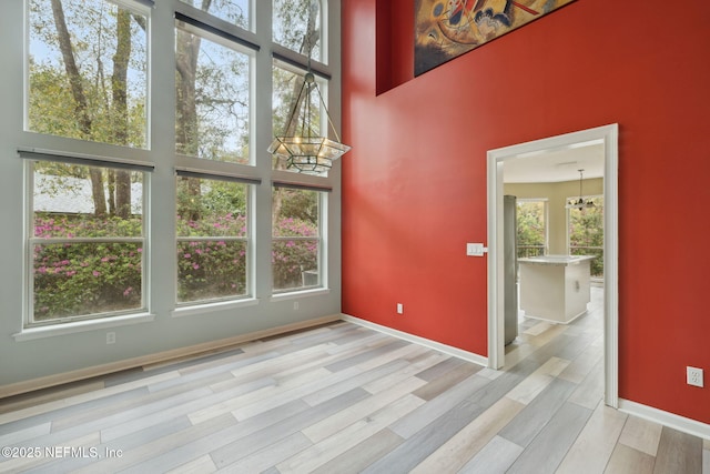 interior space with a notable chandelier, wood finished floors, baseboards, and a towering ceiling