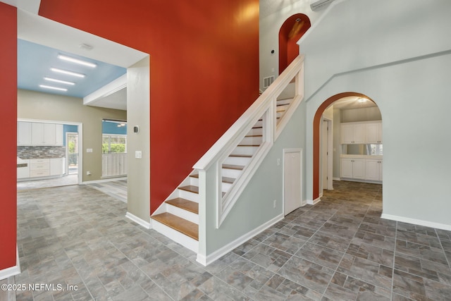 stairway featuring baseboards, arched walkways, and stone finish floor