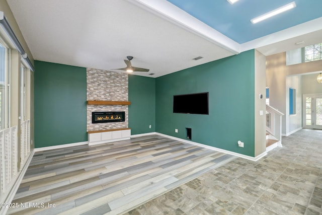 unfurnished living room featuring visible vents, a ceiling fan, stairway, a fireplace, and baseboards