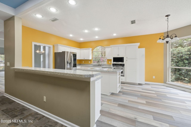 kitchen with a notable chandelier, appliances with stainless steel finishes, visible vents, and a sink