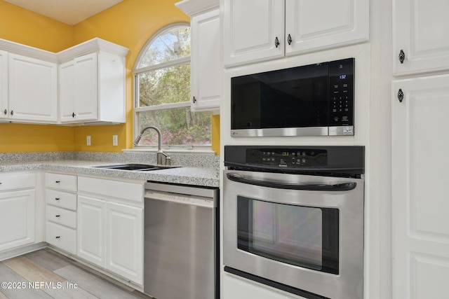 kitchen with a sink, light countertops, white cabinetry, and stainless steel appliances