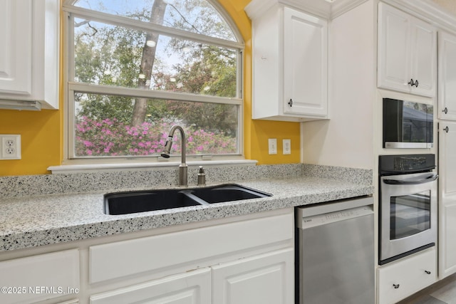 kitchen featuring a sink, light stone countertops, appliances with stainless steel finishes, and white cabinetry