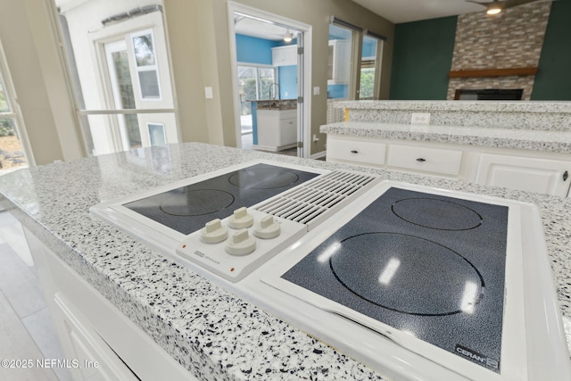 kitchen with light stone counters, white cabinets, and range