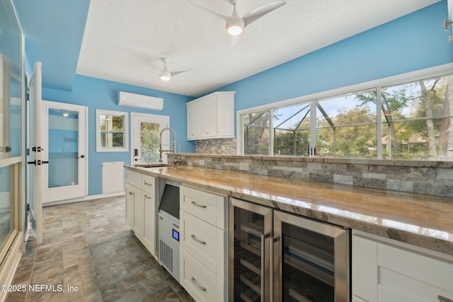 kitchen featuring backsplash, stone finish flooring, ceiling fan, an AC wall unit, and a sink