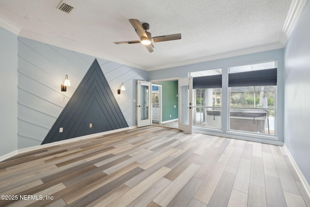 unfurnished room with visible vents, ornamental molding, a textured ceiling, wood finished floors, and baseboards