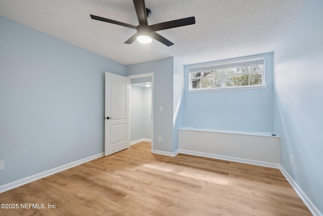 unfurnished bedroom with a ceiling fan, wood finished floors, baseboards, and a textured ceiling