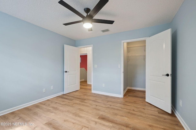 unfurnished bedroom featuring visible vents, baseboards, light wood-style floors, and a textured ceiling