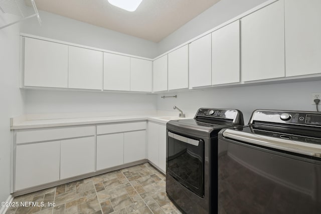 laundry area with a sink, cabinet space, washing machine and dryer, and stone finish floor